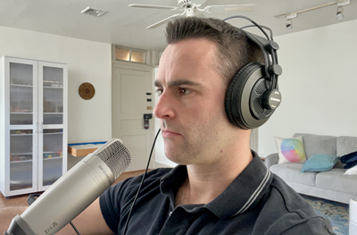 Andrew Dean with headphones and a microphone, preparing to record a podcast episode.
